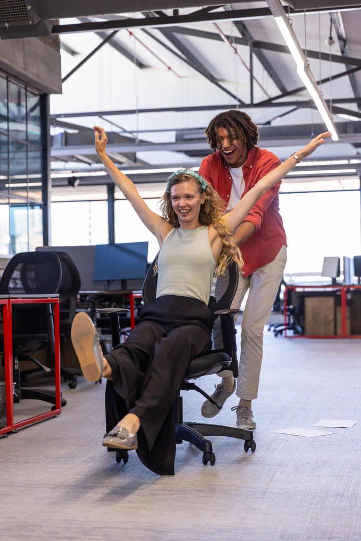 Playful Coworkers Enjoying Office Break on Rolling Chair