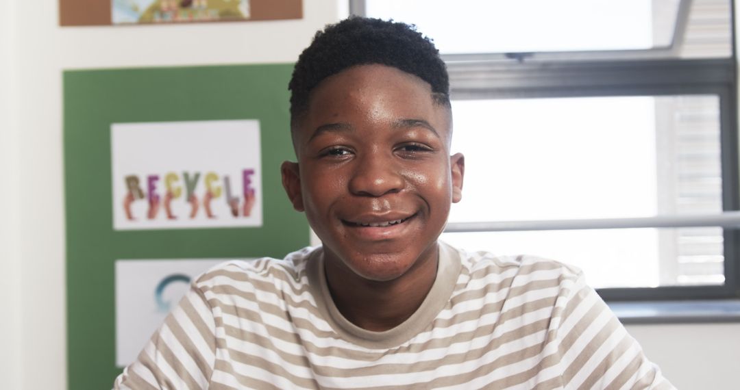 Smiling Teenage Student with Recycling Posters in Classroom