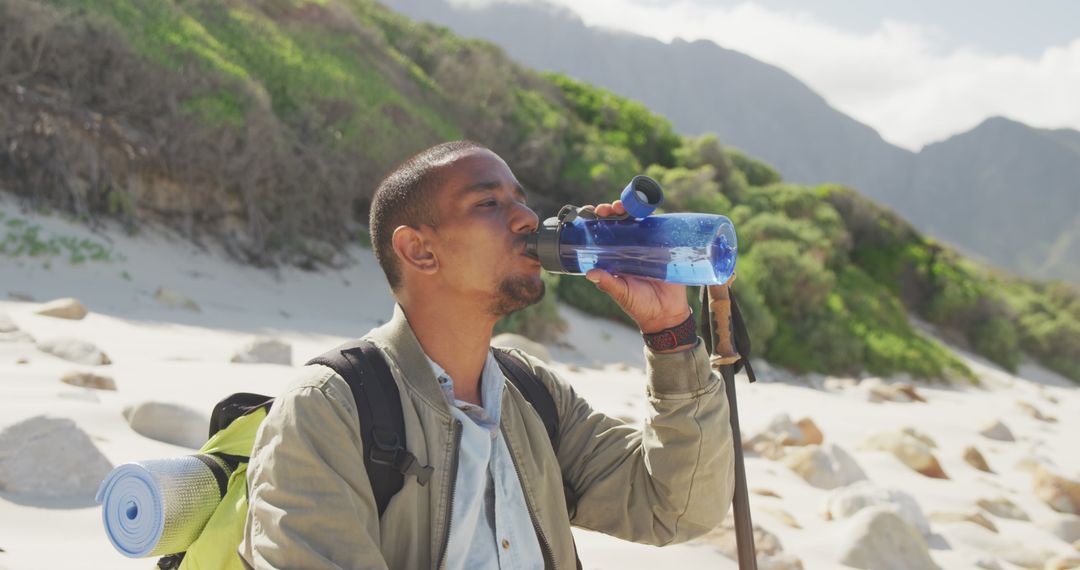 Male Hiker Drinking Water on Rocky Beach - Free Images, Stock Photos and Pictures on Pikwizard.com