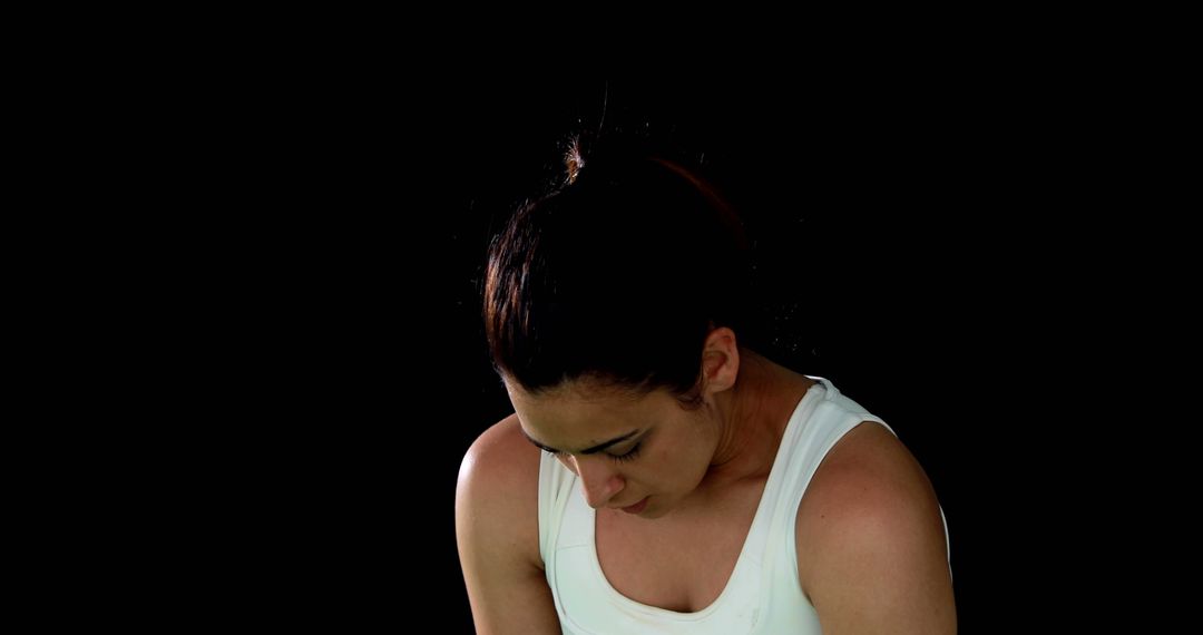 Close-up of female athlete looking down against dark background - Free Images, Stock Photos and Pictures on Pikwizard.com