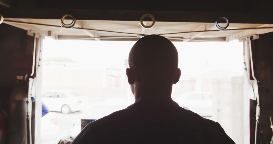 Silhouette of Man Standing Inside Garage Facing Outside - Free Images, Stock Photos and Pictures on Pikwizard.com