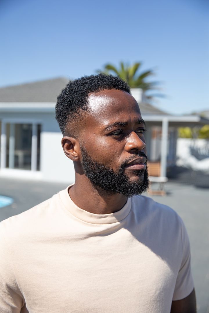 Confident Man Standing on Modern Patio under Clear Sky