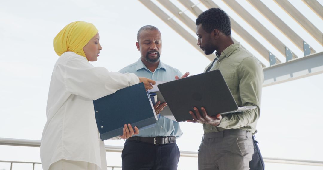 Diverse Team Collaborating on Project with Documents and Laptop