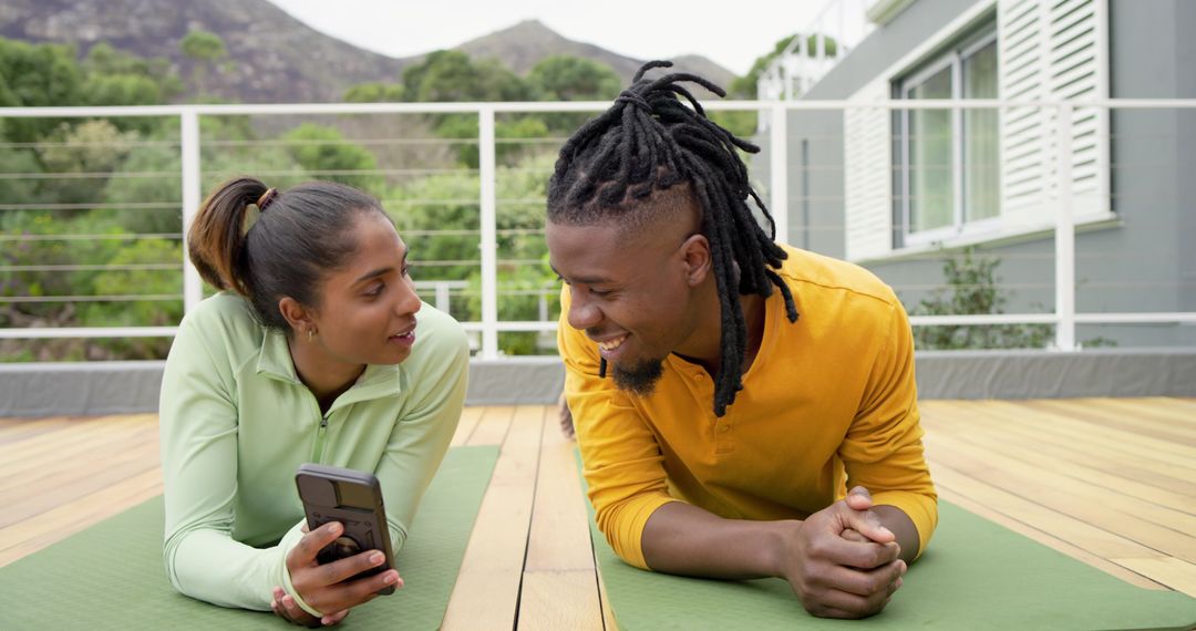 Couple Practicing Yoga on Deck Sharing Smartphone and Smiling in Morning Light