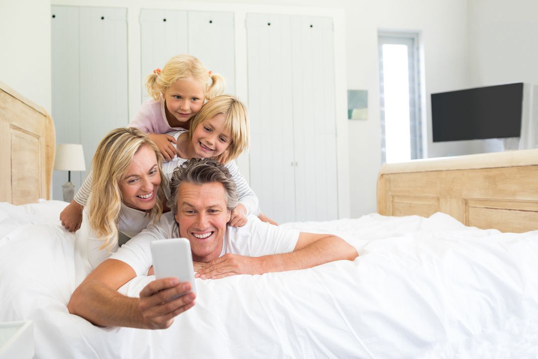 Happy family taking a selfie on mobile phone in the bed room - Free Images, Stock Photos and Pictures on Pikwizard.com