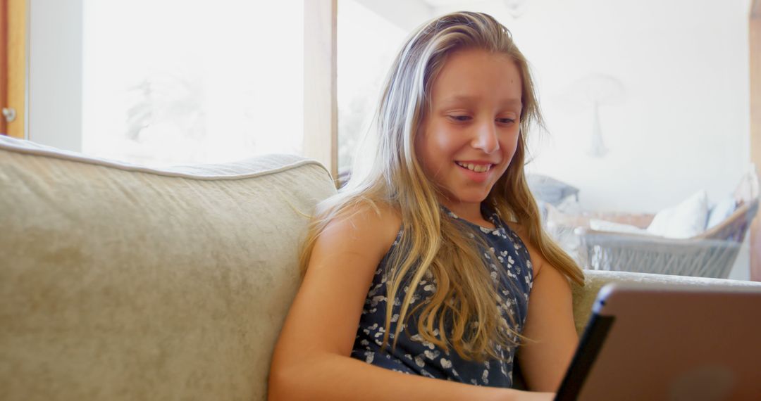 Happy Girl With Long Blond Hair Using Tablet at Home - Free Images, Stock Photos and Pictures on Pikwizard.com