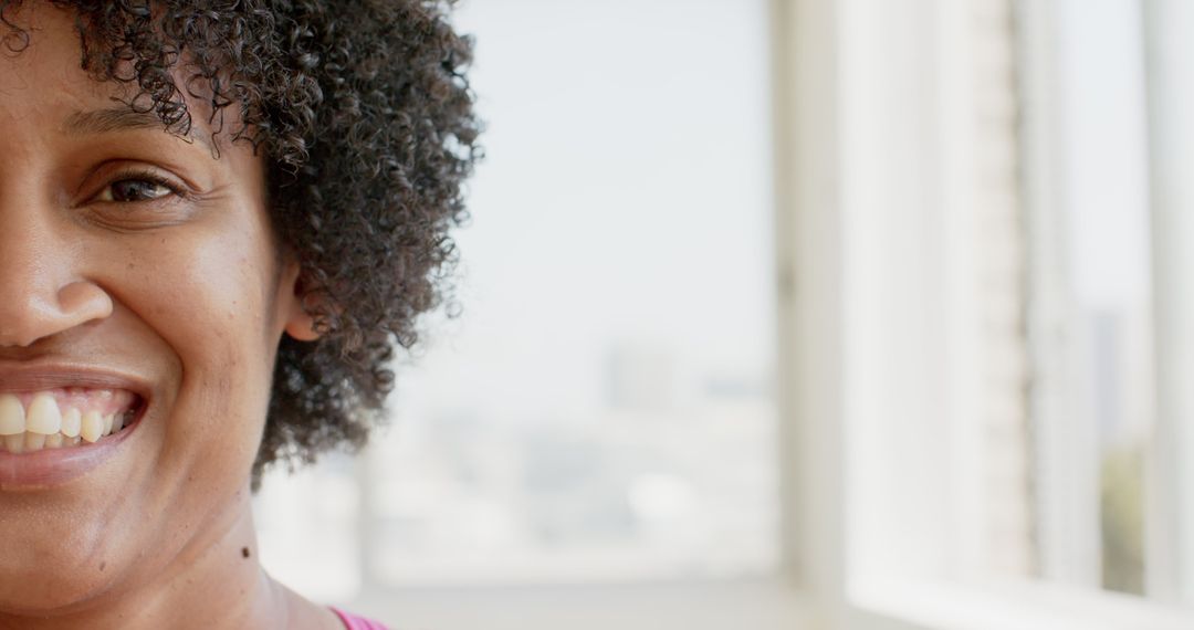 Close-Up of Smiling Biracial Woman with Curly Hair by Window