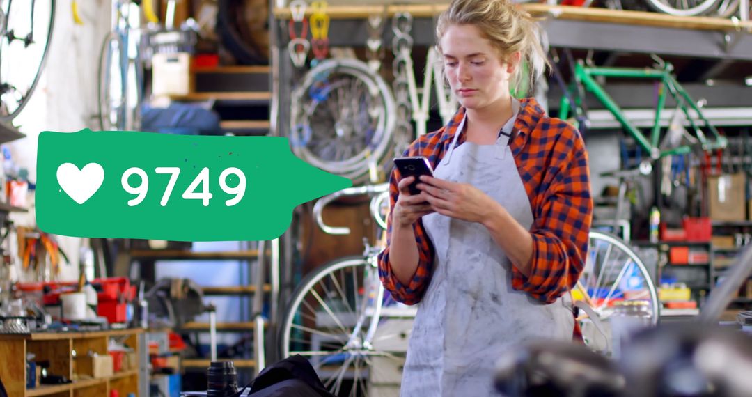 Female Bicycle Mechanic Using Smartphone in Busy Workshop