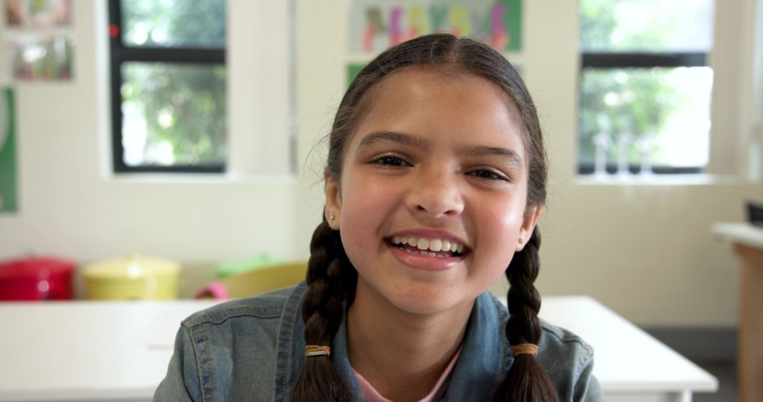 Smiling Girl Sitting in Classroom with Windows and Storage Bins