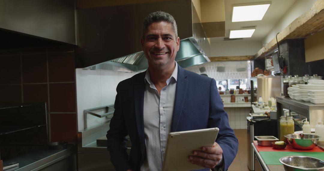 Smiling Restaurant Manager Holding Digital Tablet in Commercial Kitchen - Free Images, Stock Photos and Pictures on Pikwizard.com