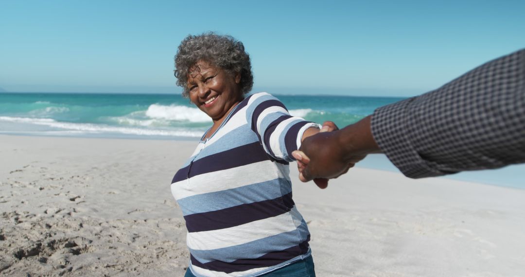 Happy Senior Woman Enjoying Beach Time Holding Hand - Free Images, Stock Photos and Pictures on Pikwizard.com