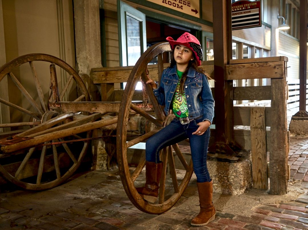 Young Girl with Pink Cowboy Hat Standing by Wooden Wagon Wheel - Free Images, Stock Photos and Pictures on Pikwizard.com