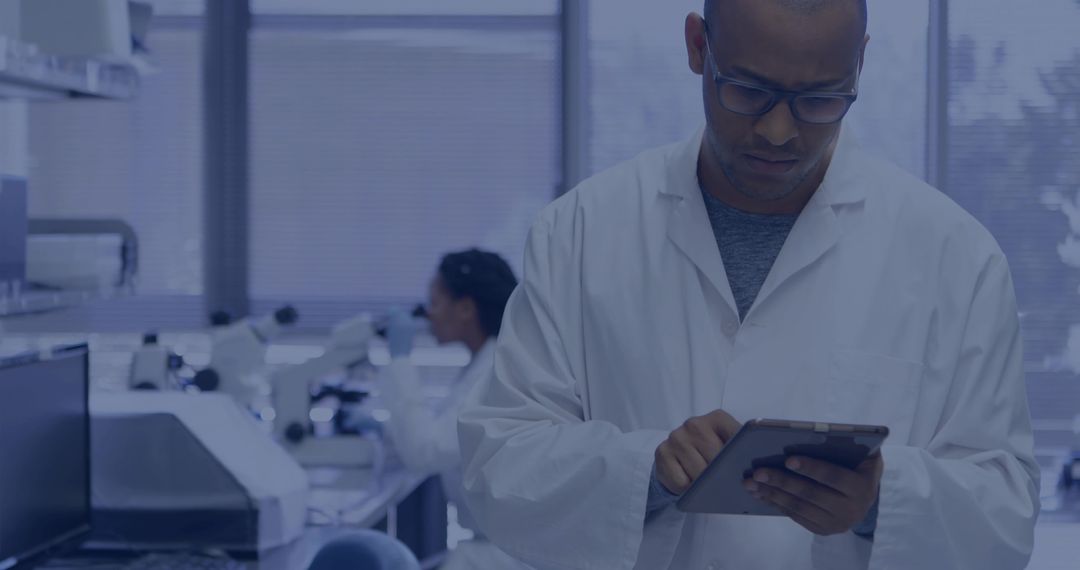 Reviewing scientist using tablet in modern laboratory with microscopes and lab equipment