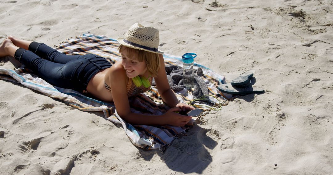 Boy Relaxing on Beach Towel with Smartphone and Hat - Free Images, Stock Photos and Pictures on Pikwizard.com