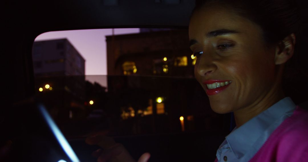 Woman Smiling While Using Smartphone in Car at Night - Free Images, Stock Photos and Pictures on Pikwizard.com