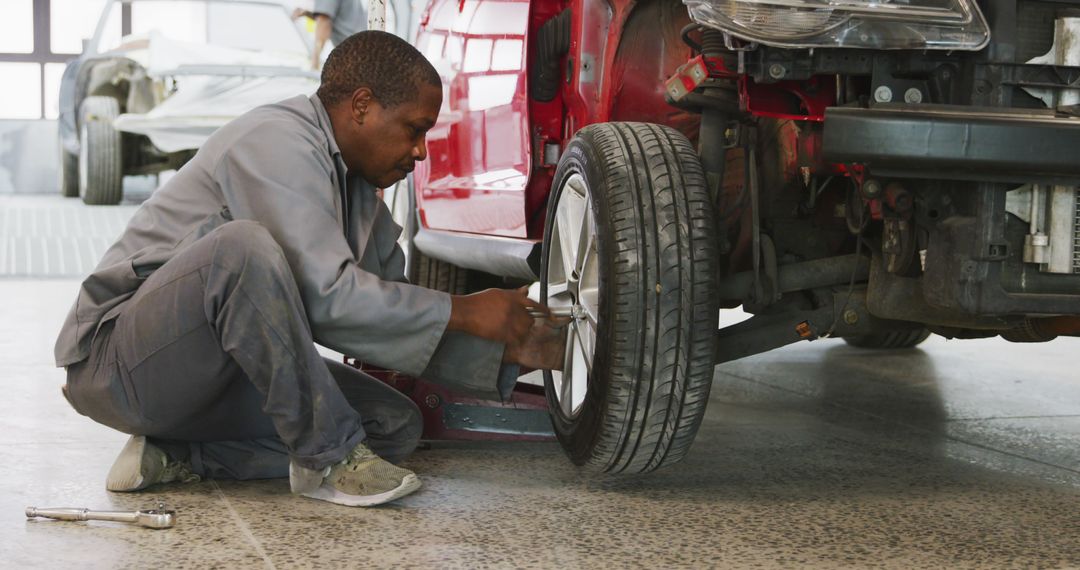 Mechanic Repairing Car's Wheel in Auto Repair Shop - Free Images, Stock Photos and Pictures on Pikwizard.com