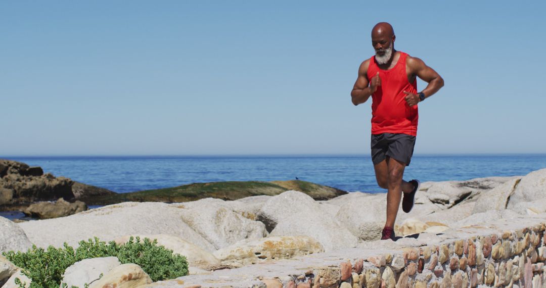 Active Senior Man Jogging By Sea On Sunny Day Wearing Red Tank - Free Images, Stock Photos and Pictures on Pikwizard.com