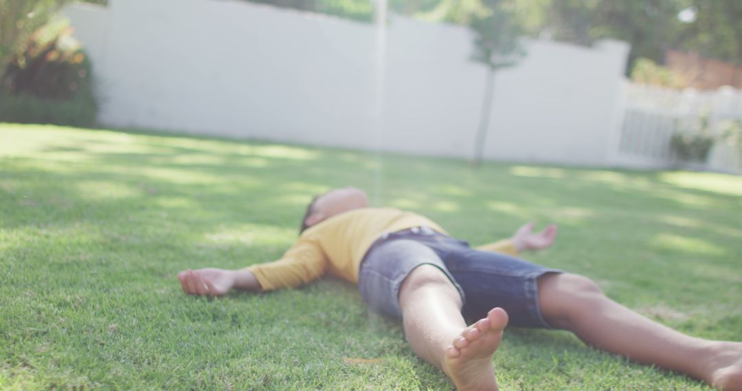 Child Relaxing Lying on Grass in Backyard on Sunny Day - Free Images, Stock Photos and Pictures on Pikwizard.com