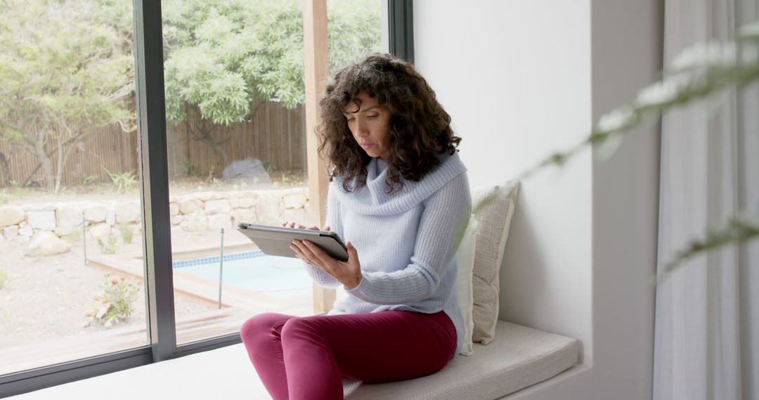 Woman Using Tablet Near Window in Cozy Living Room - Free Images, Stock Photos and Pictures on Pikwizard.com