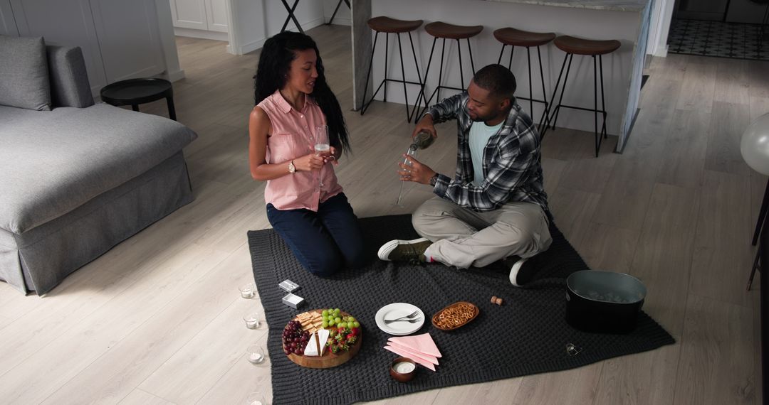Couple Enjoying Indoor Picnic with Champagne and Snacks