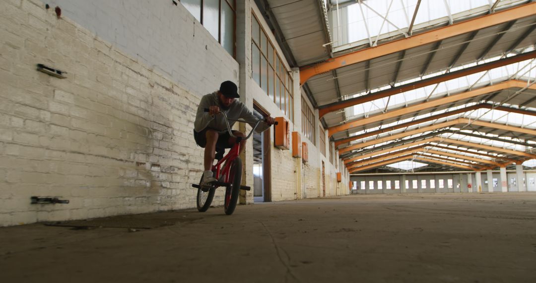 Man Riding BMX Bike in Empty Industrial Building - Free Images, Stock Photos and Pictures on Pikwizard.com