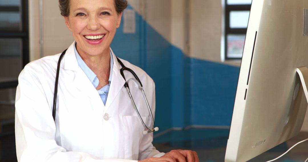 Smiling Middle-Aged Female Doctor by Computer Displaying Professional Confidence - Free Images, Stock Photos and Pictures on Pikwizard.com