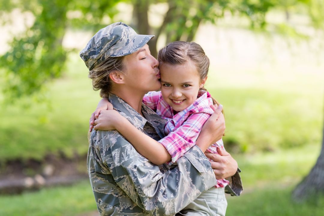 Happy female soldier kissing her daughter in park - Free Images, Stock Photos and Pictures on Pikwizard.com