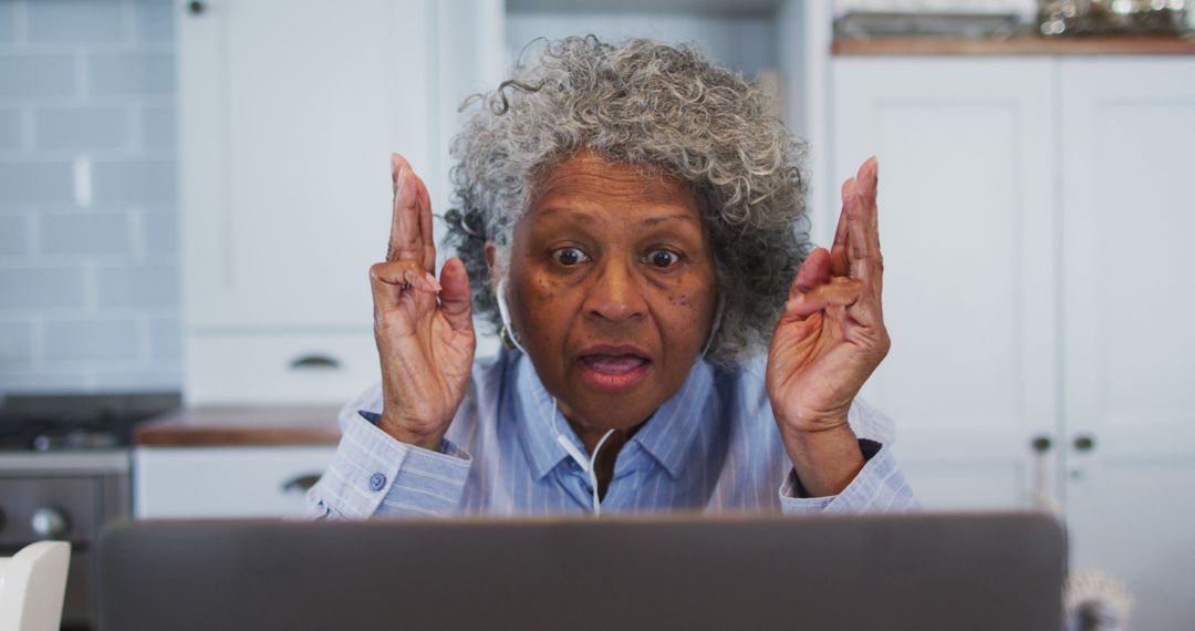 Surprised Senior Woman Looking at Laptop Screen in Kitchen - Free Images, Stock Photos and Pictures on Pikwizard.com