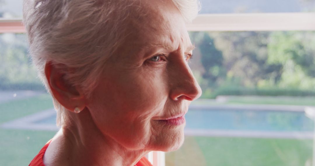 Thoughtful Senior Woman Looking Out Window at Home - Free Images, Stock Photos and Pictures on Pikwizard.com