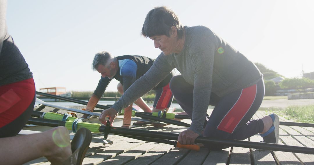 Senior Rowing Team Preparing Boat on Riverbank