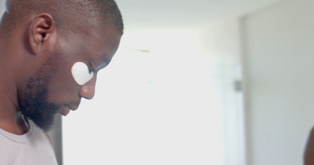 Man Applying Under Eye Patch in Natural Light Setting
