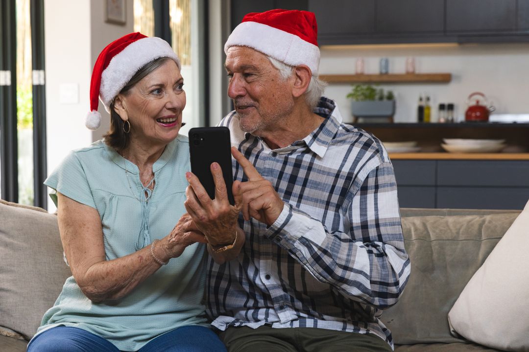 Happy Senior Couple with Santa Hats Embracing Technology