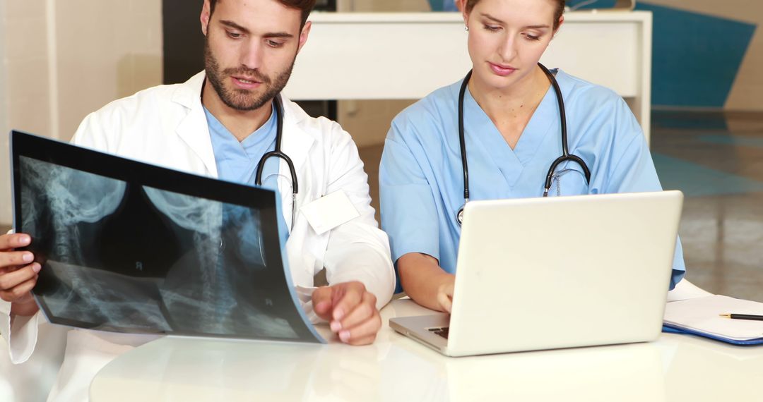 Medical practitioners analyzing X-ray and using laptop in hospital - Free Images, Stock Photos and Pictures on Pikwizard.com