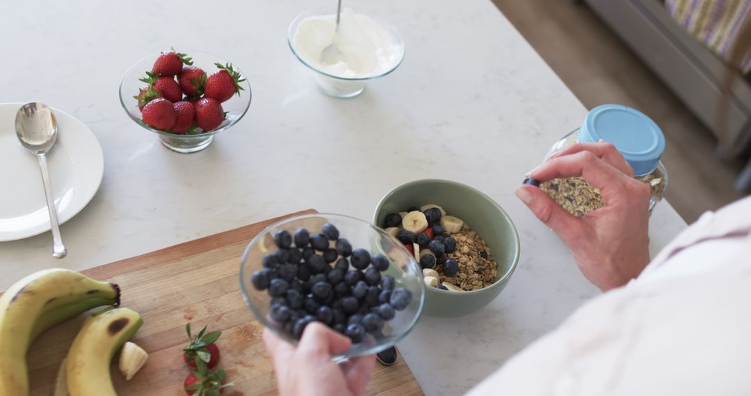 Hands Preparing Healthy Breakfast with Fruits and Granola