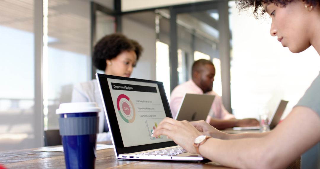 Diverse Team Analyzing Budget Chart on Laptop in Modern Workspace