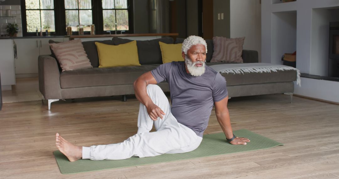 Mature Man Practicing Yoga Twist at Home on Green Mat