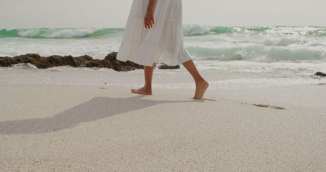 Woman Walking Barefoot on Sunny Beach with Waves and Rocks