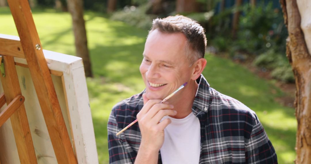 Middle-Aged Man Smiling While Painting Outdoors - Free Images, Stock Photos and Pictures on Pikwizard.com