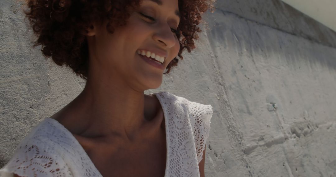 Cheerful Woman with Curly Hair Laughing Outdoors - Free Images, Stock Photos and Pictures on Pikwizard.com