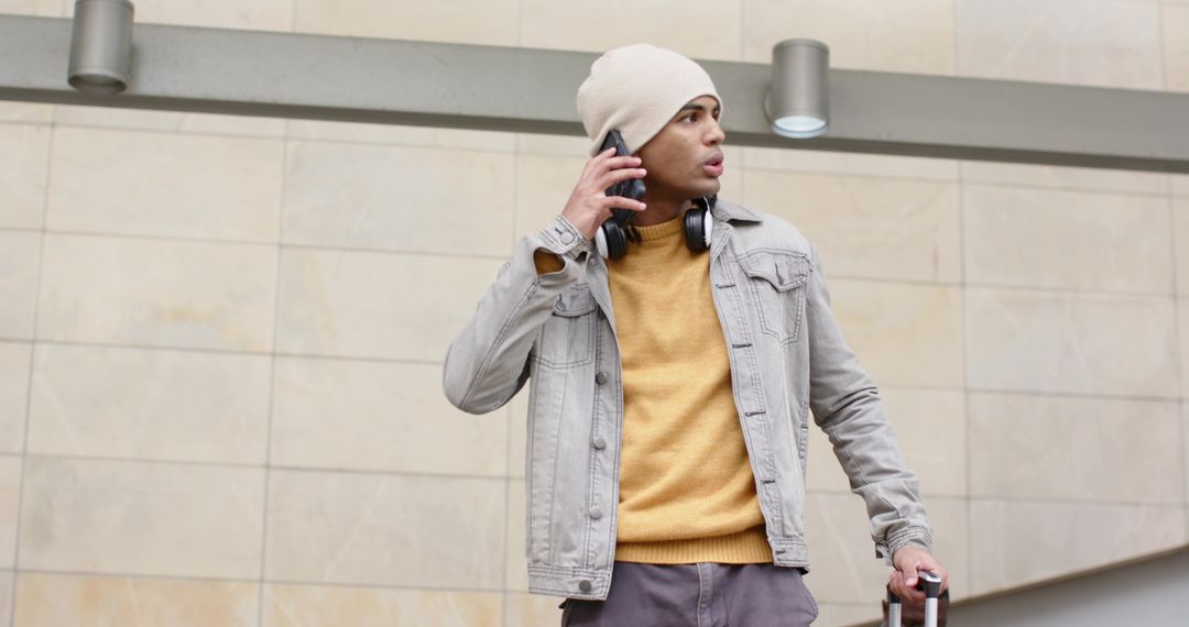 Urban traveler checking smartphone while pulling rolling suitcase through transit concourse