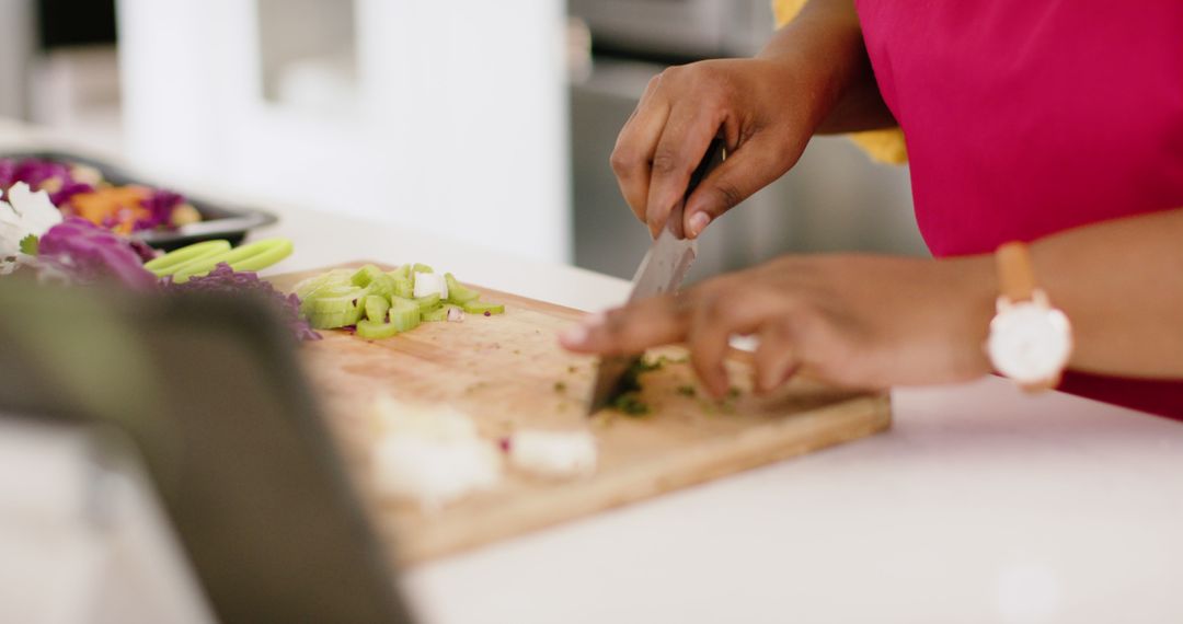 Close-up of person chopping vegetables on wooden cutting board in kitchen - Free Images, Stock Photos and Pictures on Pikwizard.com