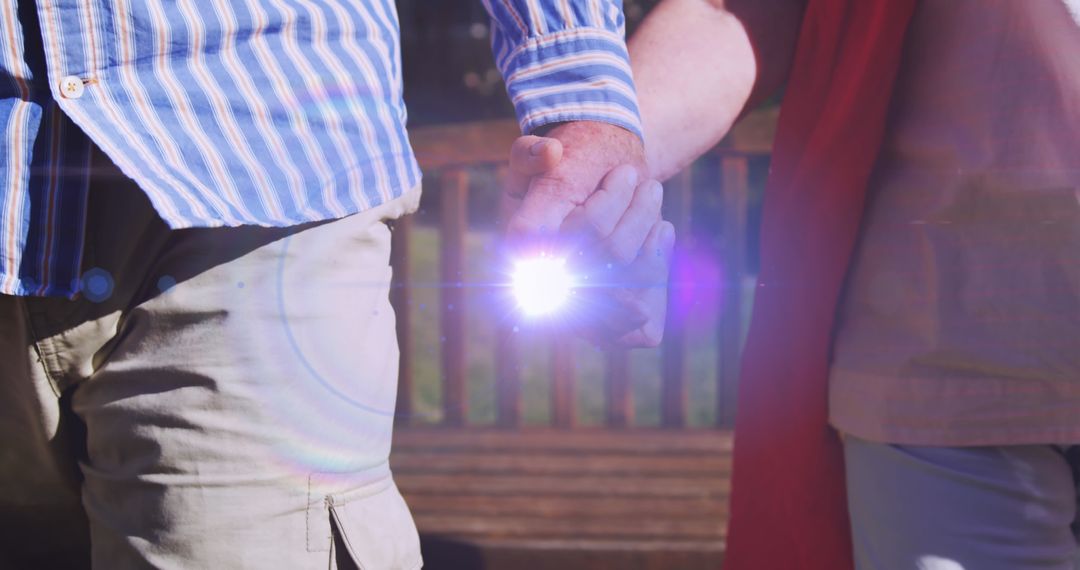 Glowing Light Illuminates Hands of Senior Couple in Park