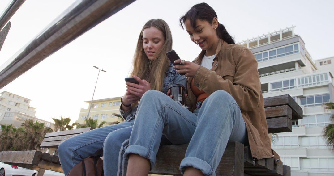 Teenagers Sitting Outdoors on Bench, Sharing and Texting on Smartphones - Free Images, Stock Photos and Pictures on Pikwizard.com