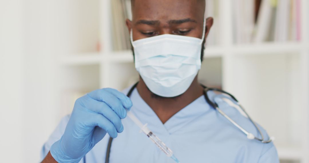 Image of african american male doctor in face mask preparing vaccine - Free Images, Stock Photos and Pictures on Pikwizard.com