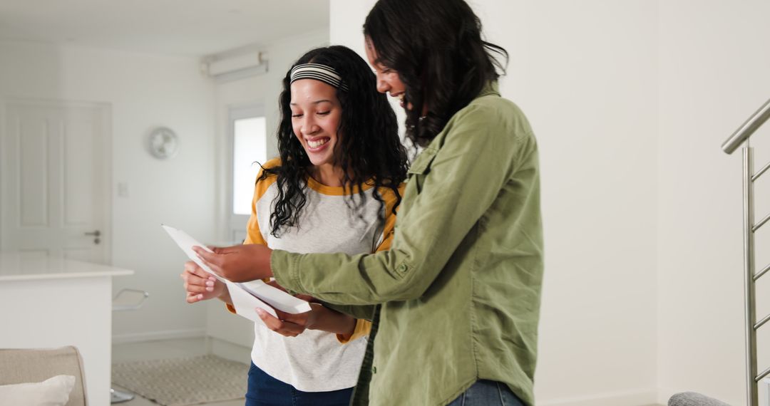 Mother and Daughter Sharing Happy Moment Reading Documents at Home