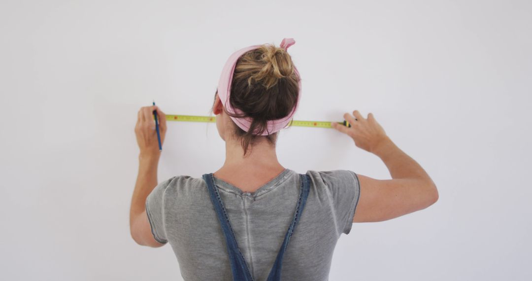 Woman Renovating Home with Measuring Tape on Wall - Free Images, Stock Photos and Pictures on Pikwizard.com