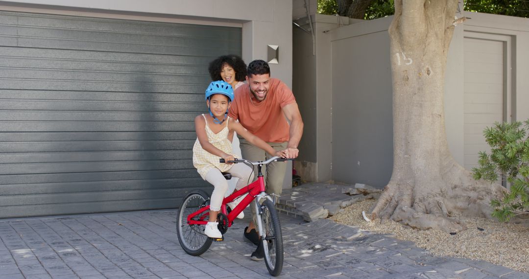 Father Teaching Daughter to Ride Bicycle While Mother Smiles Supportively
