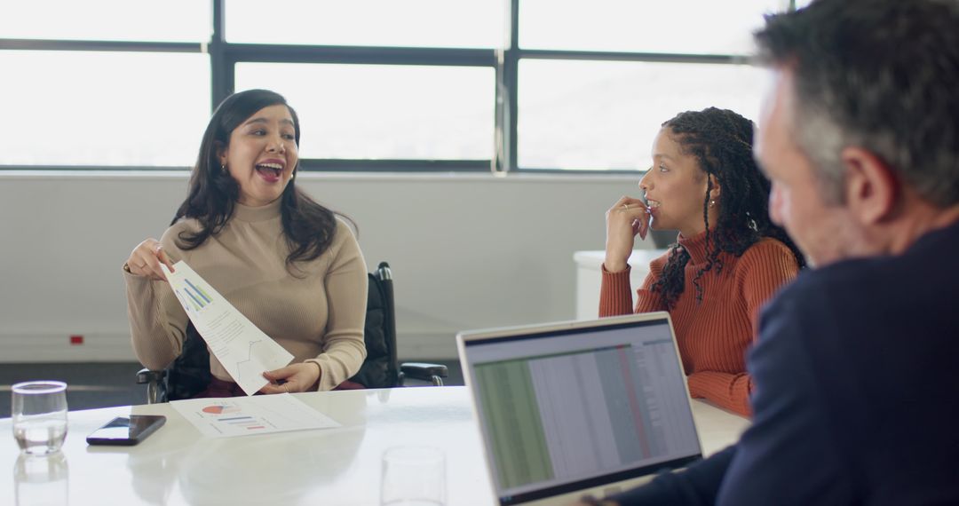 Diverse team collaborating in boardroom with wheelchair user leading presentation