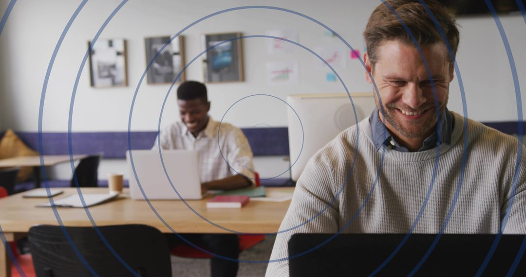 Smiling professional working on laptop in coworking space, collaboration and productivity