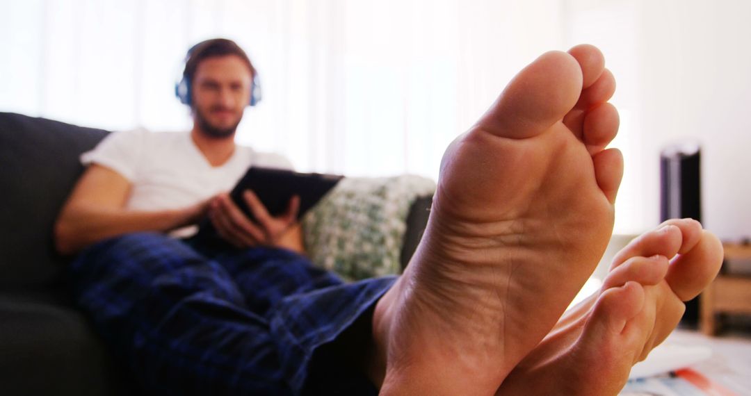 Man Relaxing on Couch with Tablet Listening to Music - Free Images, Stock Photos and Pictures on Pikwizard.com